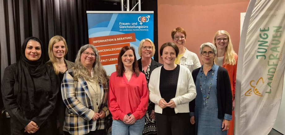 Zehn Frauen stehen lächelnd für ein Gruppenfoto nebeneinander. Im Hintergrund stehen Roll-Ups vom Frauen- und Gleichstellungsbüro und den Jungen Landfrauen. Die Atmosphäre wirkt freundlich und professionell.