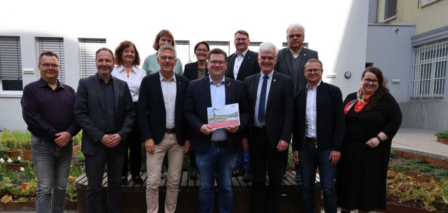 Eine Gruppe von 15 Personen steht im Innenhof eines Verwaltungsgebäudes, in der Mitte hält ein Mann ein Dokument mit dem Titel der OloV-Strategie. Es handelt sich um Vertreterinnen und Vertreter aus Kreisverwaltung, Wirtschaft, Schulen und Verbänden, die sich gemeinsam für die berufliche Orientierung von Jugendlichen im Landkreis Hersfeld-Rotenburg einsetzen.