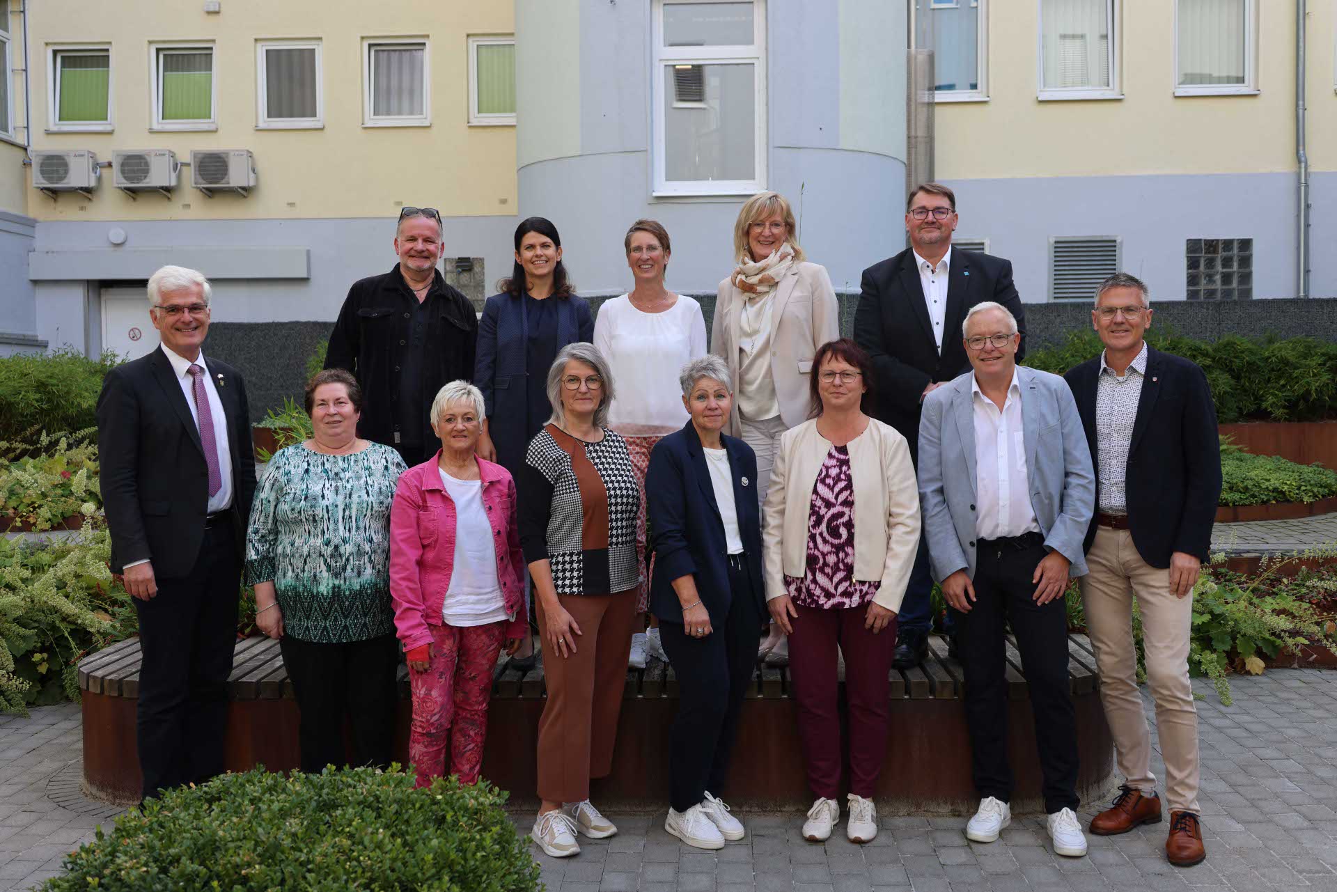Eine Gruppe von geehrten Mitarbeitenden der Kreisverwaltung steht gemeinsam mit Landrat Torsten Warnecke und Erstem Kreisbeigeordnetem Dirk Noll für ein Gruppenfoto im Innenhof des Landratsamtes.