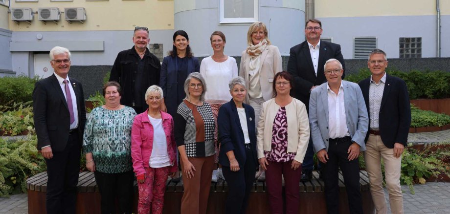 Eine Gruppe von geehrten Mitarbeitenden der Kreisverwaltung steht gemeinsam mit Landrat Torsten Warnecke und Erstem Kreisbeigeordnetem Dirk Noll für ein Gruppenfoto im Innenhof des Landratsamtes.