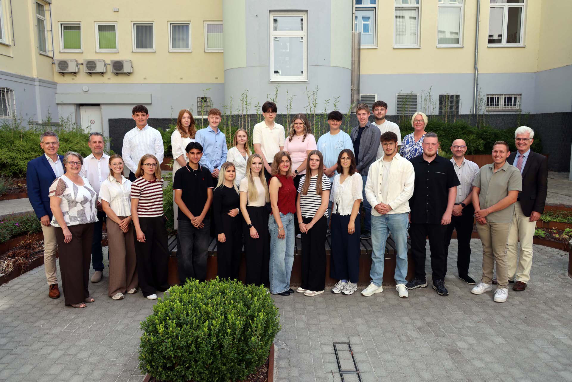 Eine Gruppe von rund 25 Personen steht im Innenhof der Kreisverwaltung. Sie schauen in die Kamera und freuen sich.