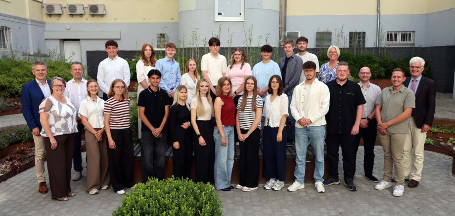 Eine Gruppe von rund 25 Personen steht im Innenhof der Kreisverwaltung. Sie schauen in die Kamera und freuen sich.