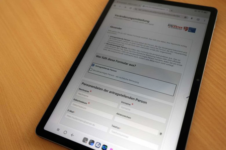 Auf einem Tablet ist ein Online-Formular zu sehen. Das Tablet liegt auf einem braunen Tisch.
