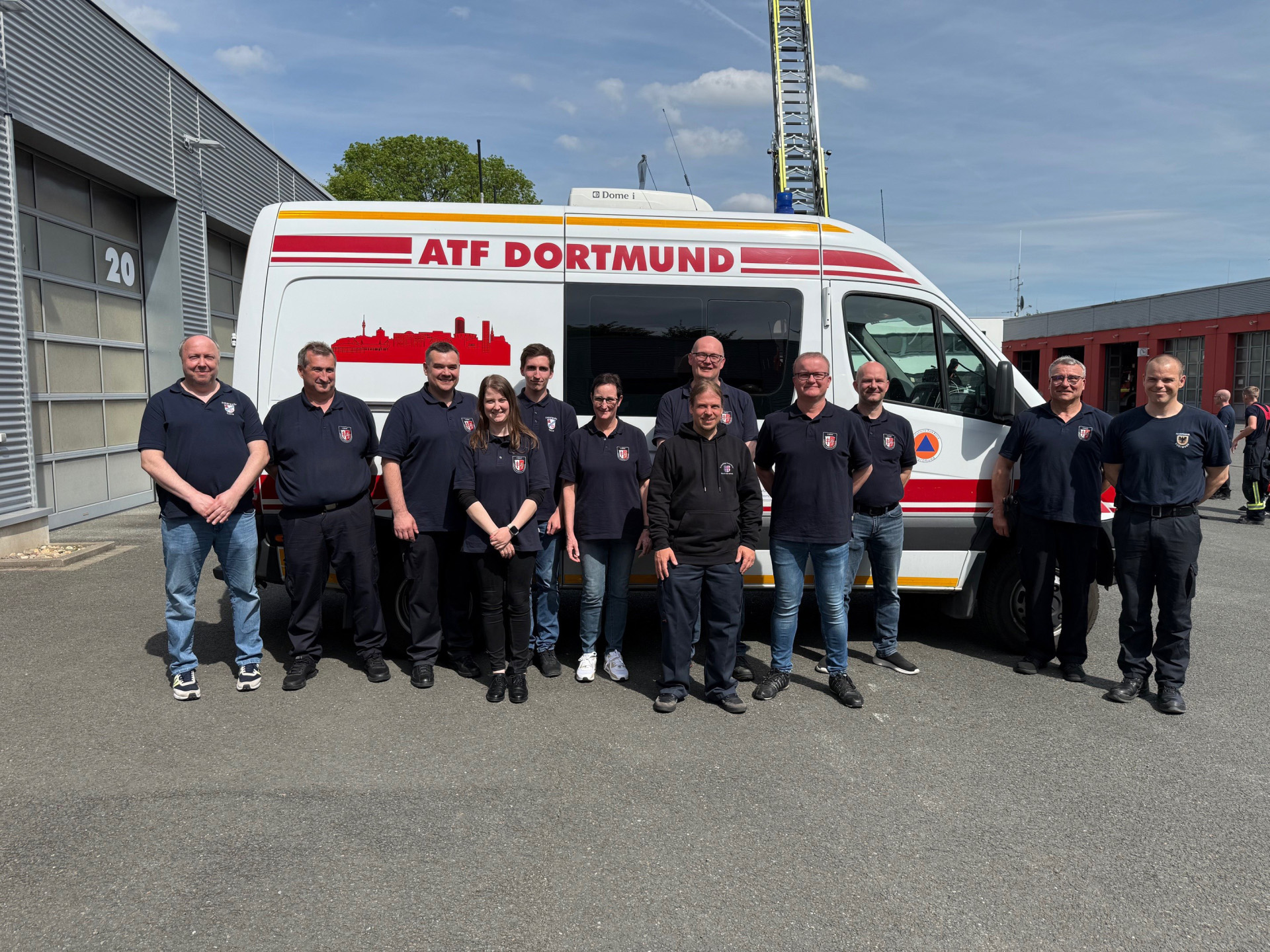 Gruppenfoto von zwölf Mitgliedern des Umwelt-Dienstes des Landkreises Hersfeld-Rotenburg vor einem Einsatzfahrzeug der Analytischen Task Force (ATF) Dortmund. Die Einsatzkräfte stehen auf dem Gelände einer Feuerwache vor dem weißen Spezialfahrzeug mit der Aufschrift „ATF Dortmund“. Das Foto entstand im Rahmen eines Fortbildungsbesuchs bei den Berufsfeuerwehren Essen und Dortmund und dokumentiert den fachlichen Austausch zu Gefahrstofflagen und Spezialtechnik.