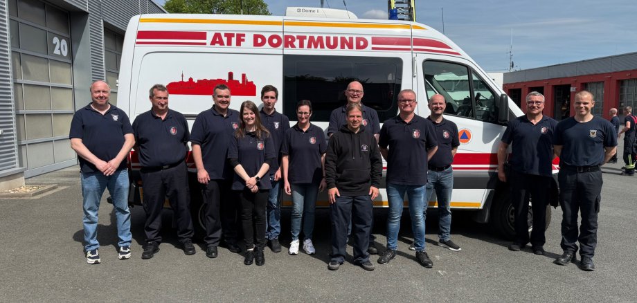 Gruppenfoto von zwölf Mitgliedern des Umwelt-Dienstes des Landkreises Hersfeld-Rotenburg vor einem Einsatzfahrzeug der Analytischen Task Force (ATF) Dortmund. Die Einsatzkräfte stehen auf dem Gelände einer Feuerwache vor dem weißen Spezialfahrzeug mit der Aufschrift „ATF Dortmund“. Das Foto entstand im Rahmen eines Fortbildungsbesuchs bei den Berufsfeuerwehren Essen und Dortmund und dokumentiert den fachlichen Austausch zu Gefahrstofflagen und Spezialtechnik.