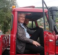 Ein Mann sitzt in auf dem Beifahrersitz in einem roten Auto.